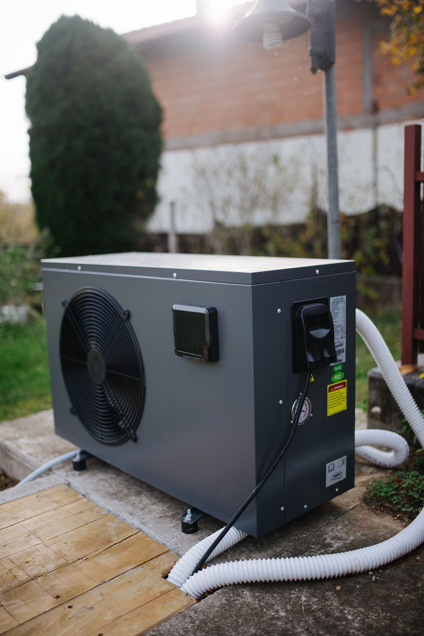 Heat pump outdoor unit installed on a platform beside a house