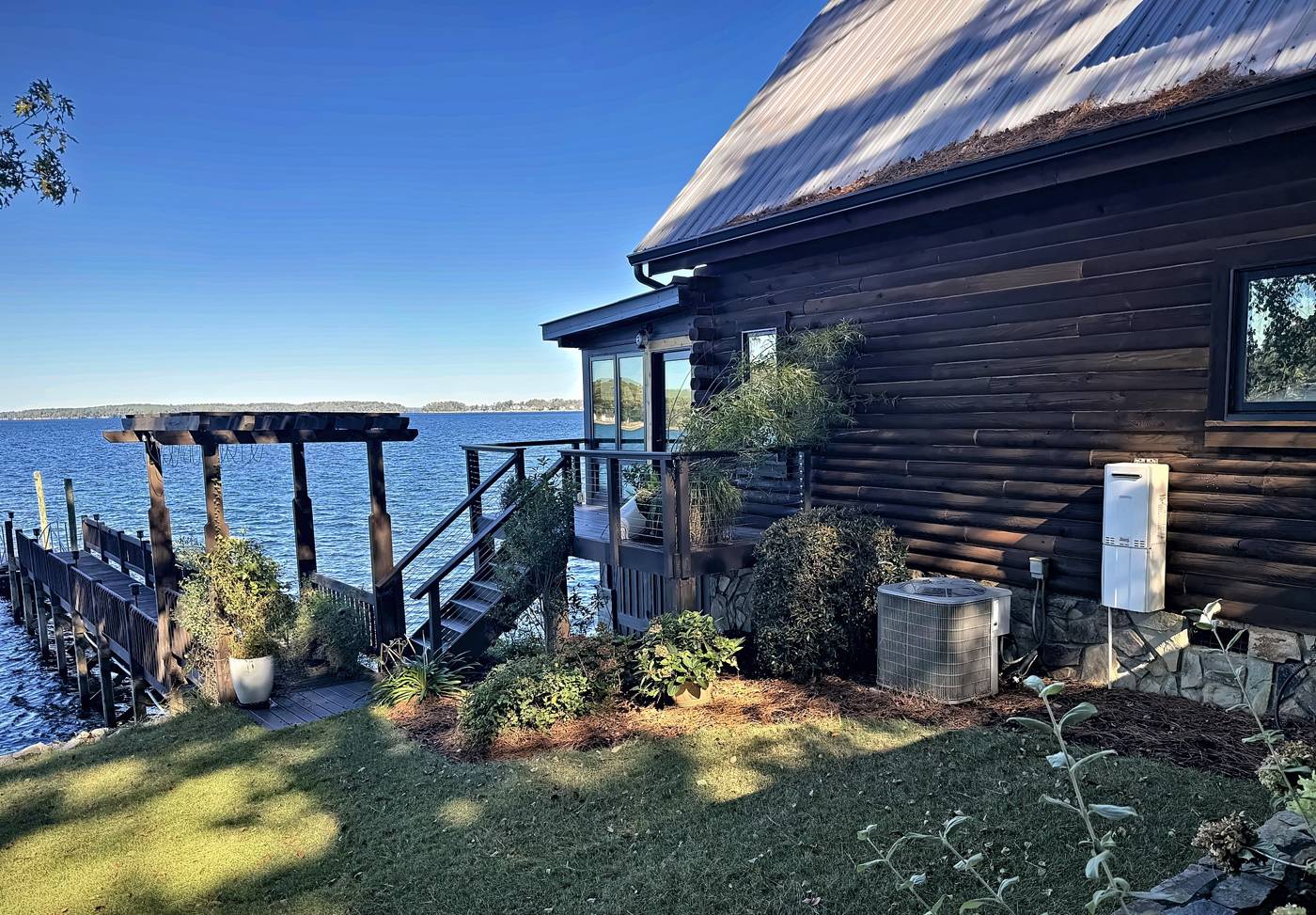 Split system condenser and tankless water heater beside a lakeside log home on Lake Murray